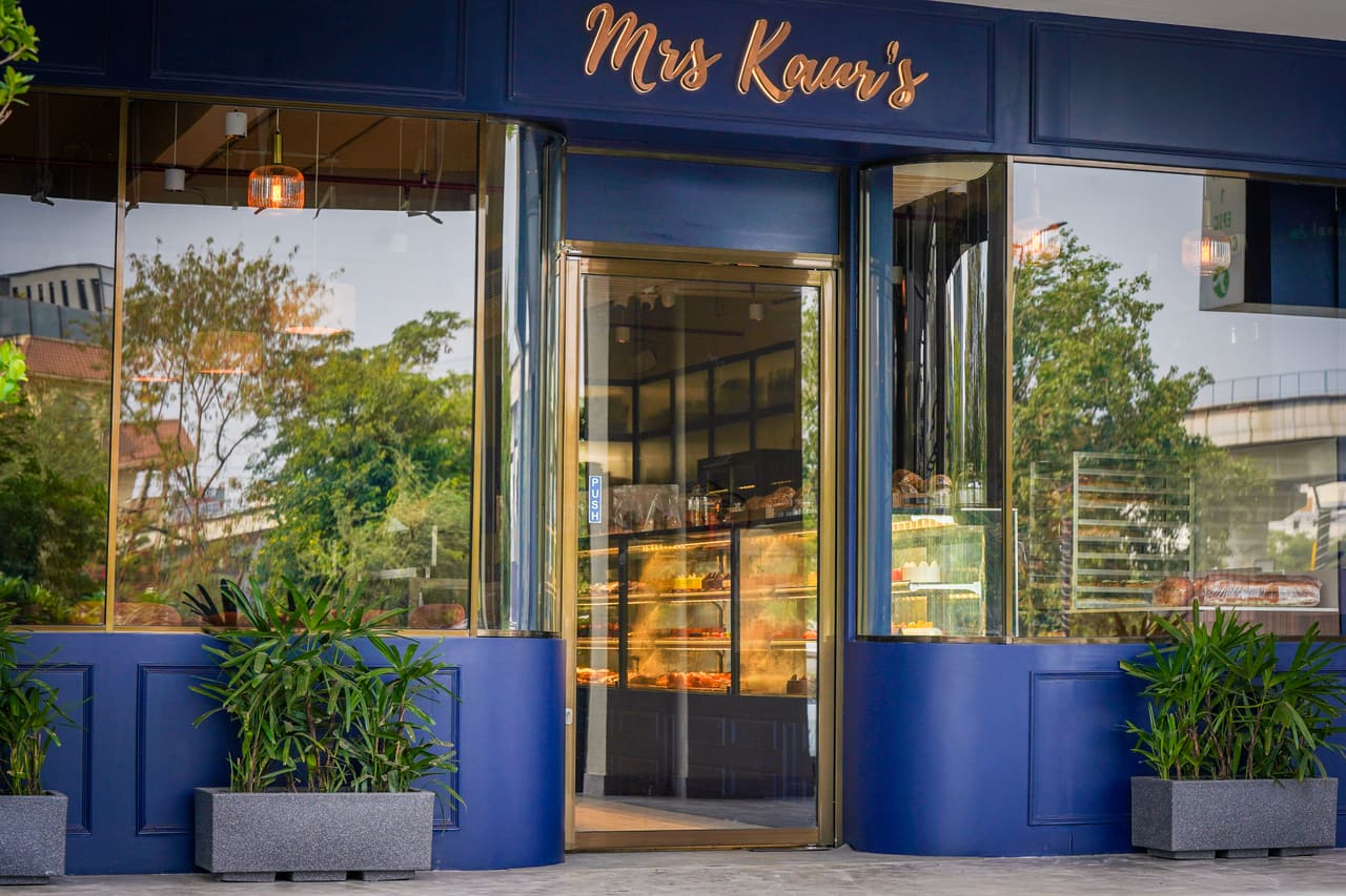 The navy shopfront of Mrs Kaur’s on Golf Course Road, with a gold script sign, glazed doors and planters in front.
