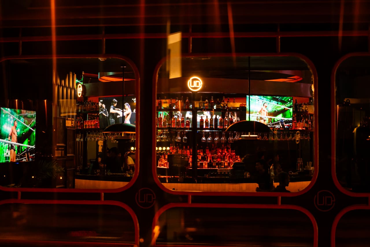 A bar seen through rounded arch openings, a football match playing on screens on either side.